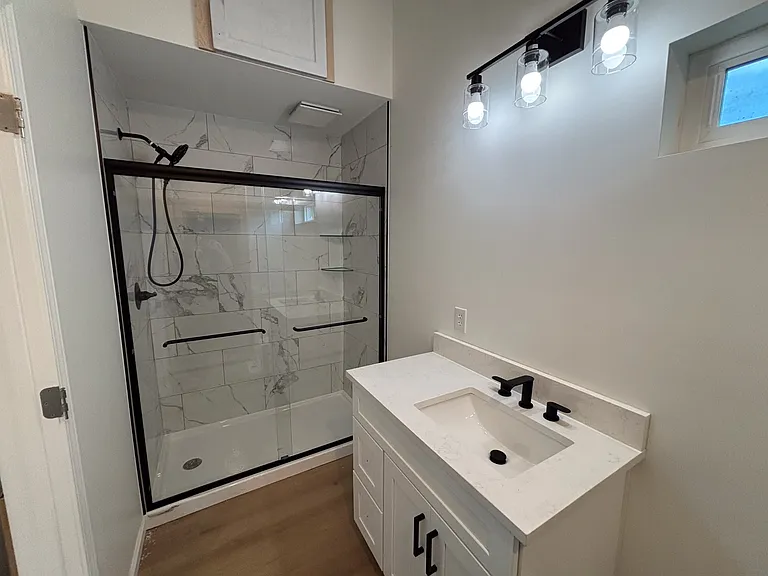 Porcelain wall tile shower with sliding glass doors.