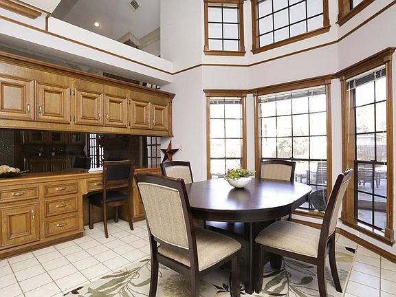 Large breakfast area with planning desk boasts wall of windows to enjoy natural light and view of sparkling pool.