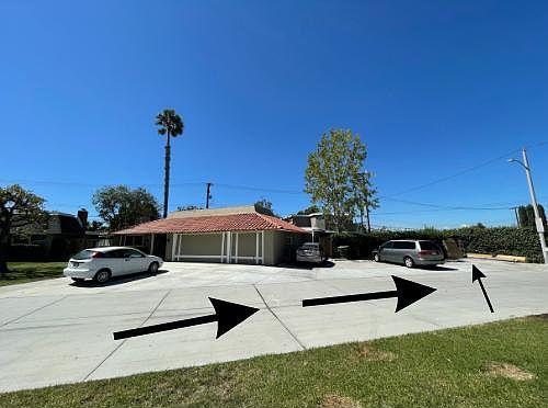 House is located towards the back of the property. Entrance is a wooden gate next to the green wall.