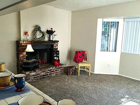 Living room with large bay window and used brick fireplace.