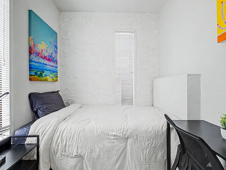 Private bedroom with a full bed, textured accent wall, and windows with blinds for light control.