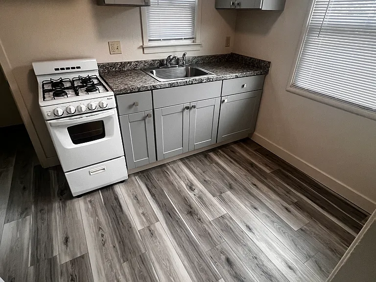 Kitchen with vinyl plank flooring, gas range, sink and cabinetry