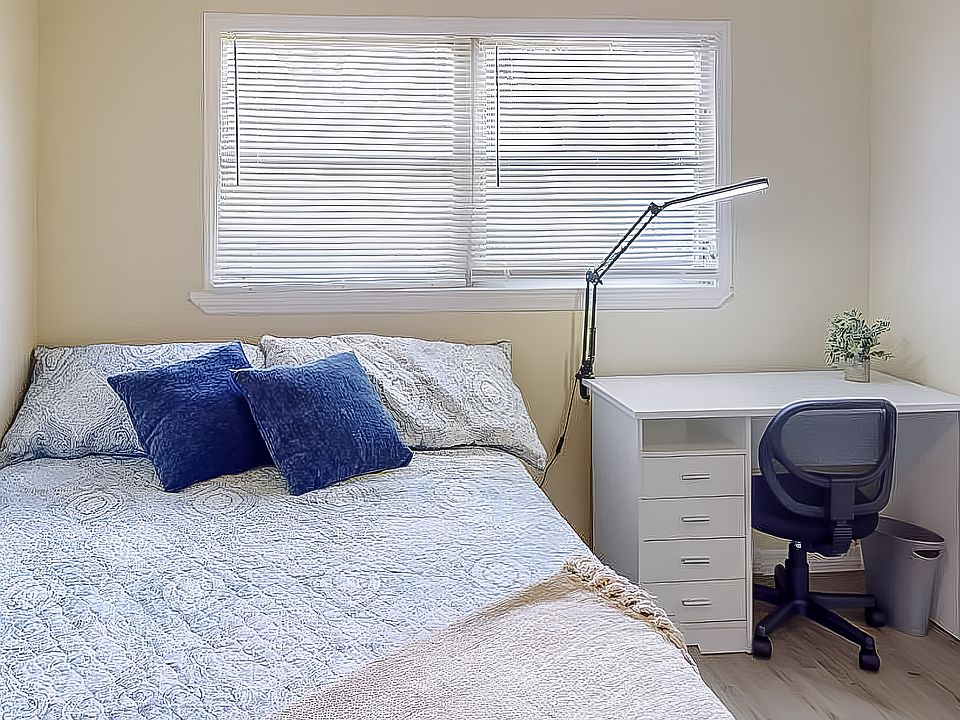 View of queen bed, desk and lamp and chair