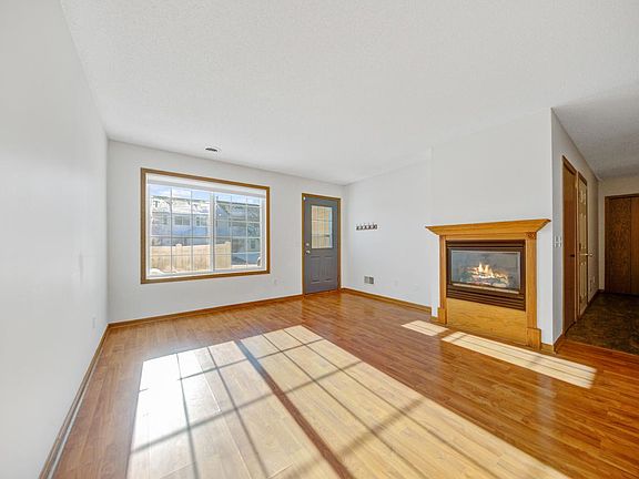 Sun-filled living area with large double window and gas fireplace, newly installed energy-efficient, light-filtering blinds