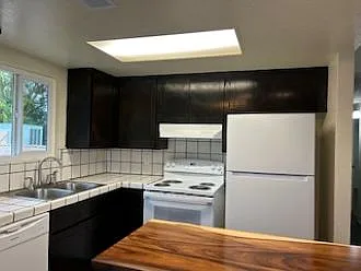 Kitchen with dishwasher, dual stainless steel sink and pot-faucet, electric stove/oven, refrigerator, and island work station
