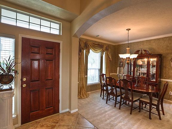 A solid wood door with upper transom window and side lite opens to the dramatic 18' Foyer with diagonally placed tile and arched openings to the Dining Room on the left and Living Room on the right. Ahead is the Den.