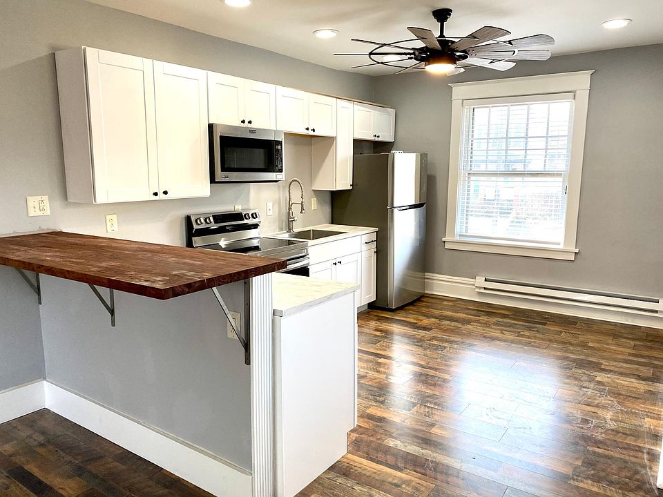 Kitchen with brand new stainless steel appliances and butcher block seating area.