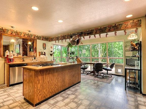 Kitchen with cook-top island and eating area with wall of windows