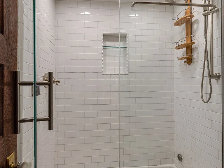 Primary en-suite Updated walk-in shower with glass door, white tile, and modern fixtures.