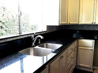kitchen looking out to the driveway, all white cabinets and black granite counter tops