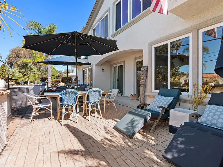 Private outdoor patio with dining table, umbrella seating, and a cozy lounge area
