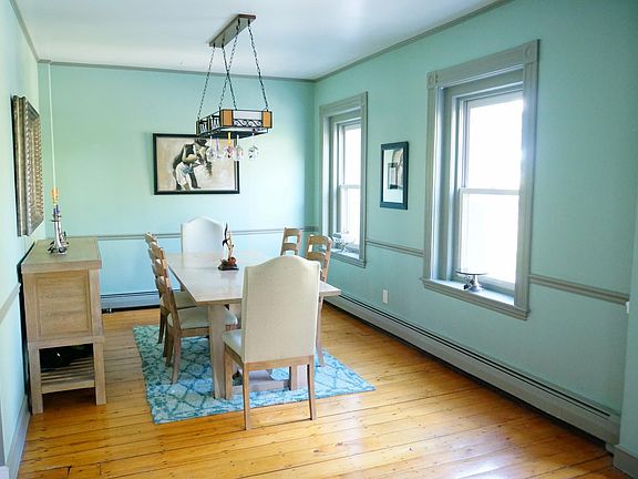 Opposite the living space, the large dining space includes crown, chair and floor moldings and two large windows with custom casings which also overlook Monument Square.
