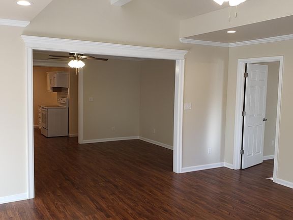 Another view of living and dining rooms with side door leading into first bedroom.