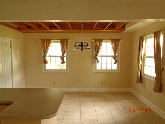 Dining room with wood ceiling and exposed rafters. Through the swinging doors is the laundry room and back door to the back yard.