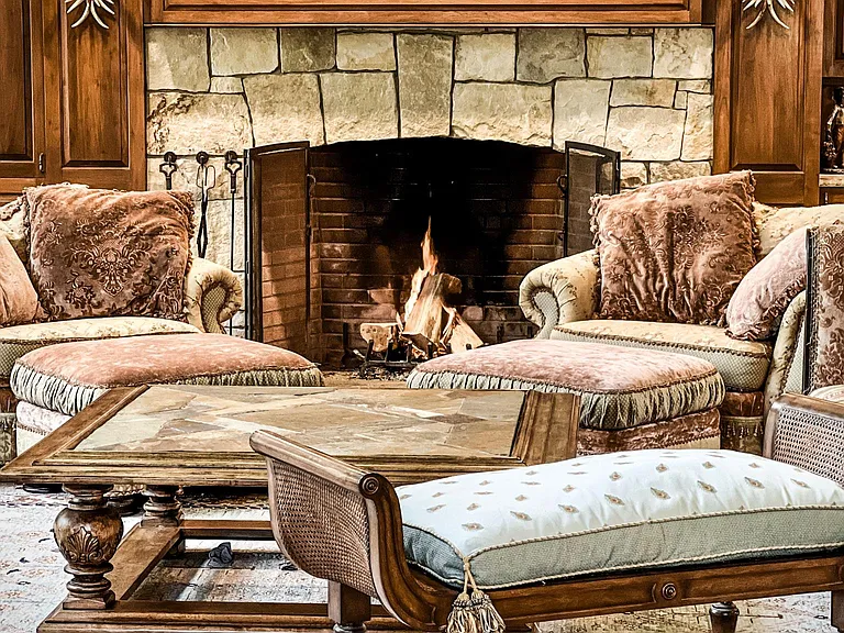 View of the richly decorated great room with seating for up to seventeen, a massive stone fireplace, and a grand piano.