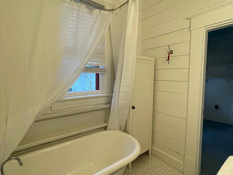 Bathroom features storage cabinet and white hex tile floor.