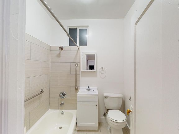 Bathroom with bathtub, tiled shower, vanity, sink, toilet, mirrored cabinet