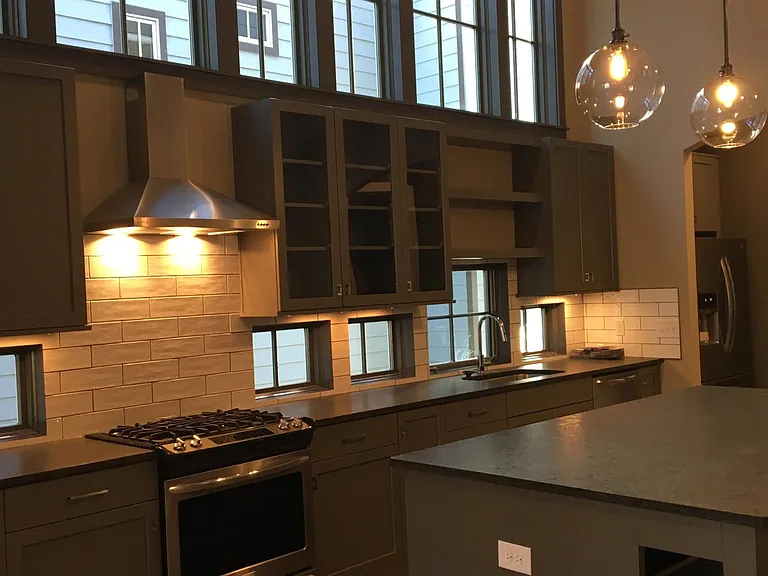 Kitchen has a wall of windows and two-story ceilings, a large island, and leathered granite countertops.