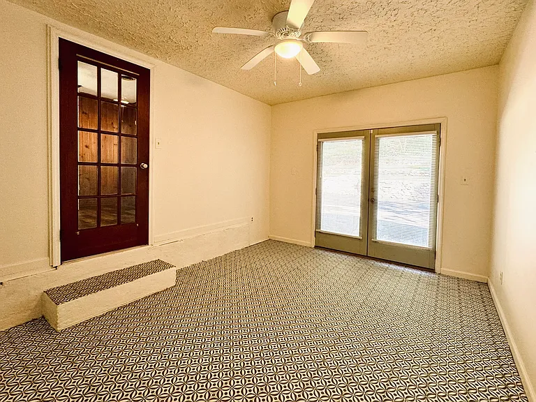 Bedroom 3 has new laminate flooring. The door to the driveway/backyard is to the right, and the door to the den is to the left.