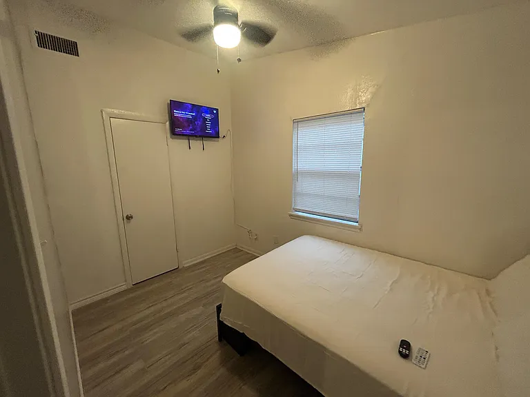 Private bedroom with a ceiling fan, window with blinds, and space for a full/queen bed; wall-mounted TV included.