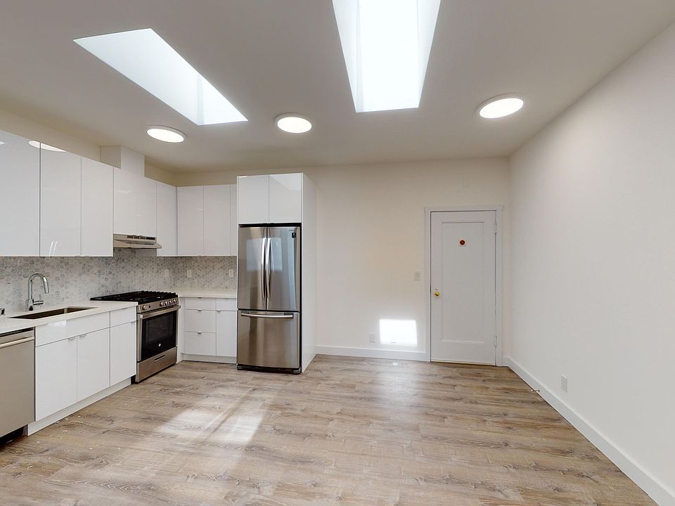 Kitchen with multiple cabinets, refrigerator, stove, range hood, and sink