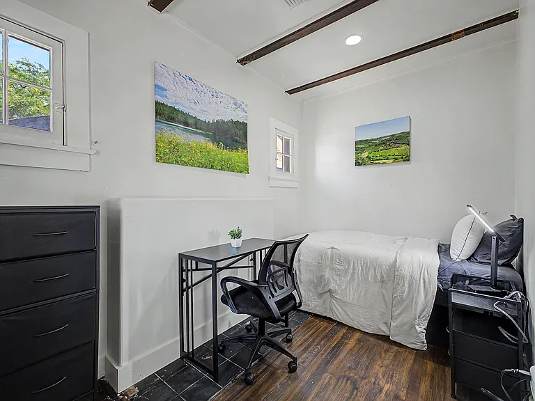 Private bedroom featuring a furnished single bed, dresser, and a dedicated desk workspace with chair for studying or remote w