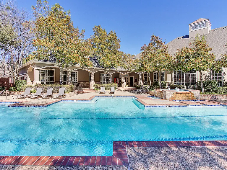 Stunning, tree-lined swimming pool with tanning deck and lounge seating
