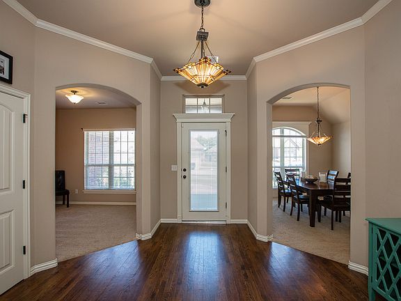 Wide open Foyer welcomes guests in style with gorgeous hardwood flooring, tiffany-inspired light fixture, entry door with enclosed blinds and extensive trim moulding and large coat closet.