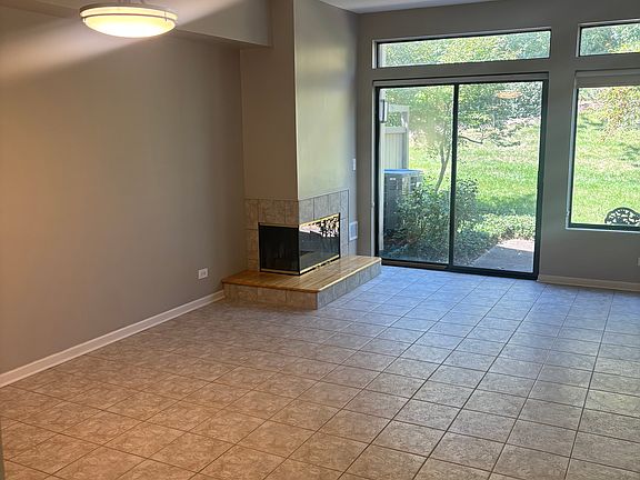 Great room view from hallway highlighting the fireplace, sliding glass door and window letting in natural light.