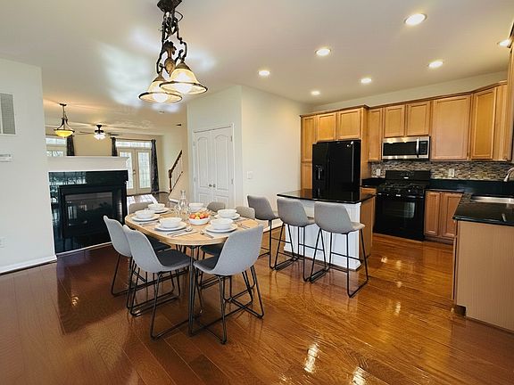 Spacious kitchen with French door pantry, black granite island, glass title under cabinets, black granite counters, two sided gas fireplace, real hardwood floor.

**This image is vitually staged with table chairs and stools for illustrative purposes.**