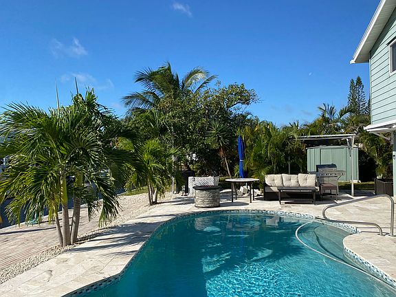 Fire pit and BBQ at poolside, with sunshade.