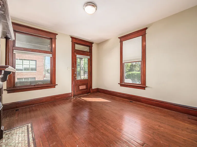 Living room with privacy blinds and mail slot in door, original wood floors and wood trim.