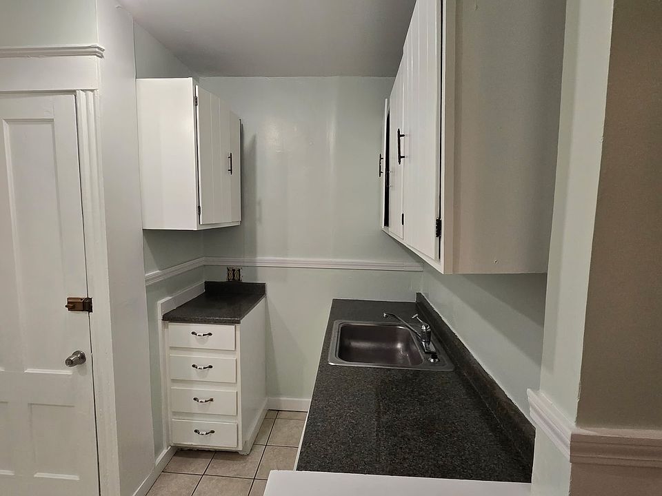 Kitchen counters and cabinets with sink window to neighbors lot. Door leads down back stairwell.