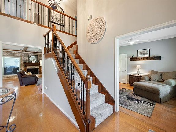 Spacious entry with high ceiling, wrought iron staircase, wood floors and updated lighting