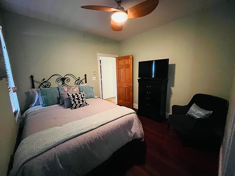 Master bedroom with queen bed and sitting chair