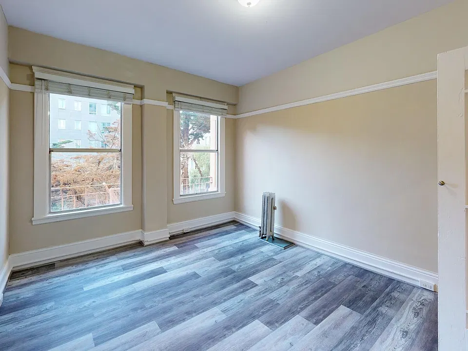 Bedroom with two large windows and a wood-like floors