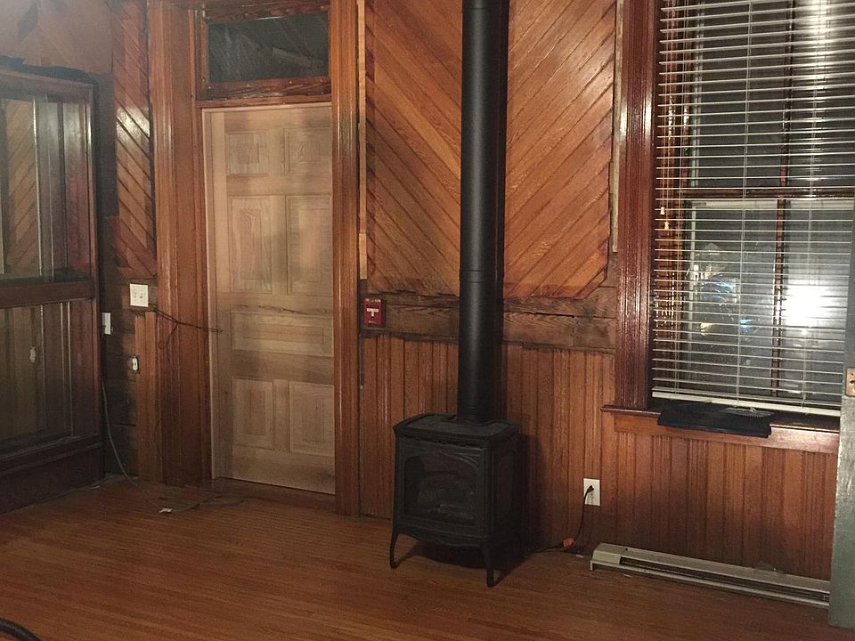 Living room with gas stove with glass front. Built in shelves in corner. Exterior door to fire escape.