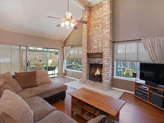 The family room boasts dentil crown molding, laminate flooring, high ceiling, ceiling fan and a fireplace with brick surround that extends to the ceiling.