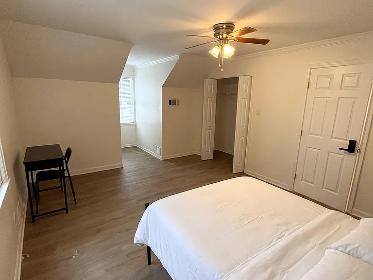 Spacious bedroom with vaulted ceiling, ceiling fan, wide-plank flooring, and a closet for easy storage.
