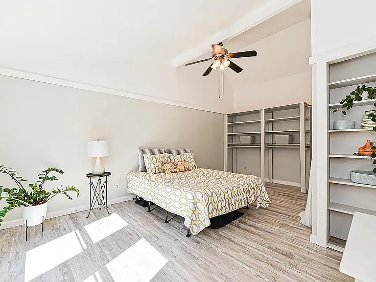Sunny bedroom with built-in shelving and generous closet storage.