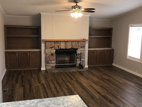 Great room featuring a wood burning fireplace. It's an open floor plan with the kitchen & dining areas.