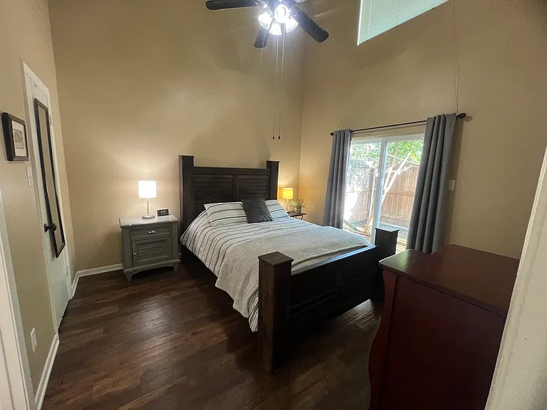 Primary suite downstairs with private sliding glass door to patio area and vaulted ceiling and large walk in closet
