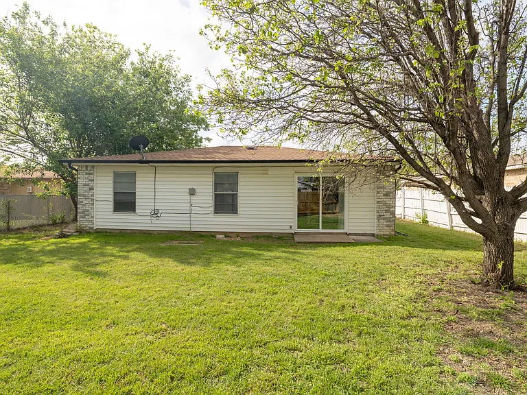 Spacious private backyard with a lush green lawn and a large mature shade tree.