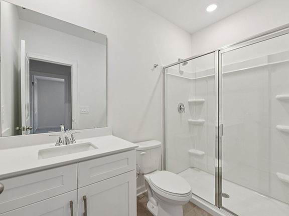 The secondary bedroom features a spacious walk-in shower and large vanity sink.
