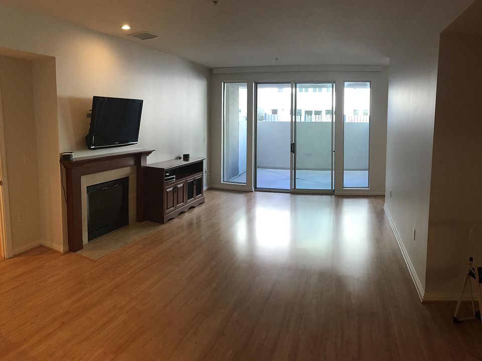 Living room with built-in electric fireplace, audio-visual storage cabinets, and mounted flat-screen television. View to private outdoor patio.