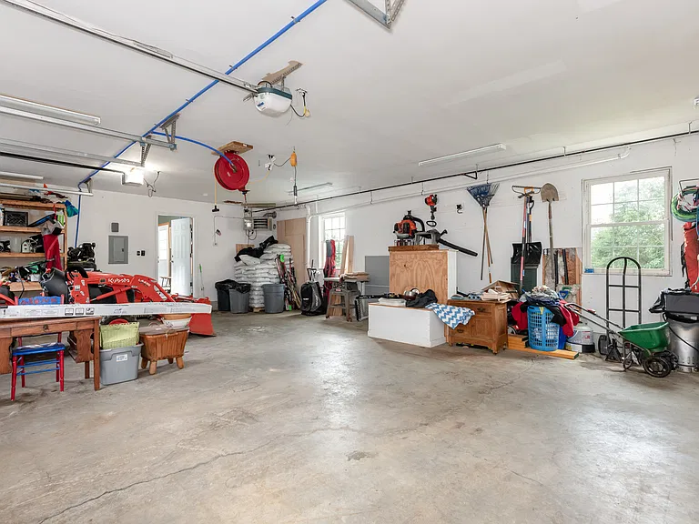 Large garage with shelving, bench, and automatic doors