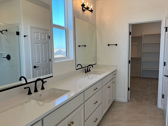 Primary Bath: A spa-inspired ensuite with dual vanities, a frameless glass walk-in shower, and designer black fixtures.