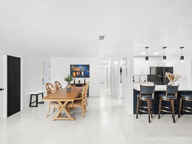Open dining area connects to a spacious kitchen with island seating, pendant lights, and stainless appliances.