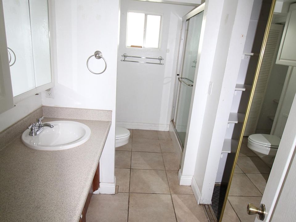 Bathroom. The sink is on the left. One closet (the bigger one) is on the right. toilet is on the left beyond the sink area. on the right is the shower. Next to the toilet is a small closet.