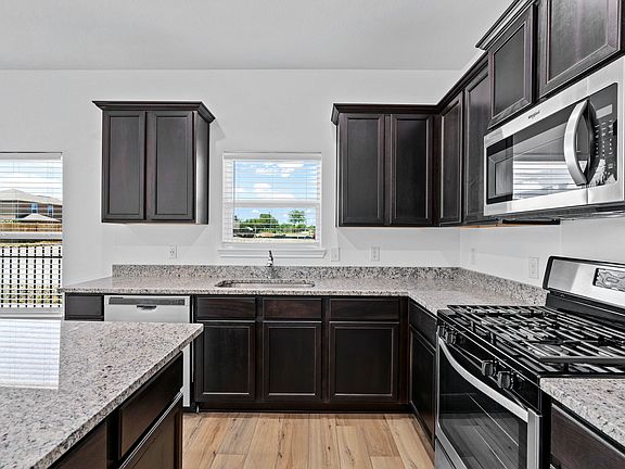 Chef-ready kitchen with granite countertops, stainless appliances, and wood-style flooring.